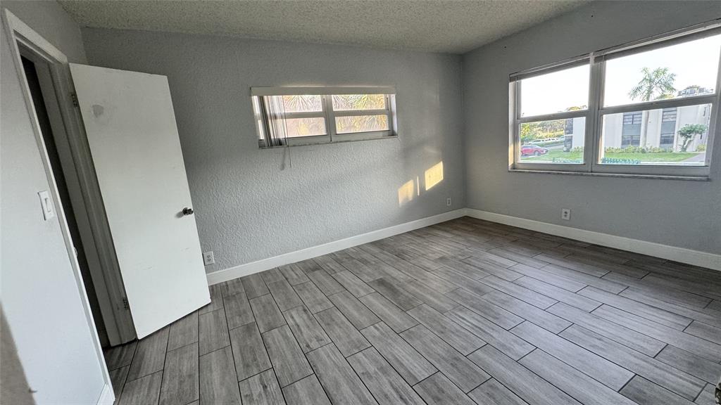 770 Southeast 2nd Avenue, Unit A207 Deerfield Beach, FL 33441 - Photo 10 of 27 an empty room with wooden floor and windows