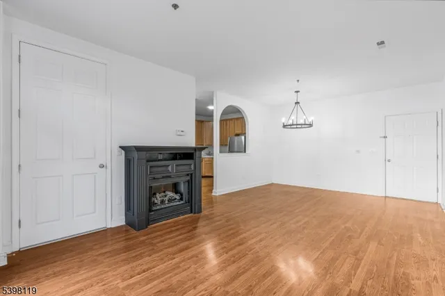 a view of empty room with wooden floor and kitchen