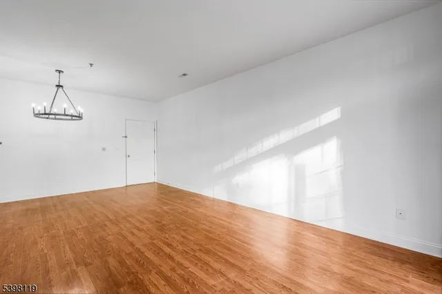 a view of empty room with wooden floor and ceiling fan