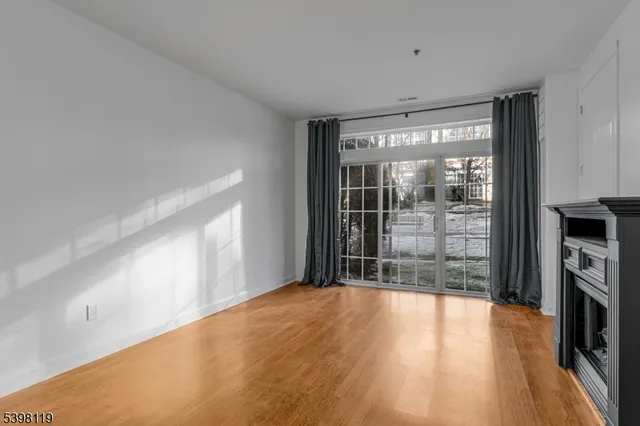 a view of empty room with wooden floor and fireplace