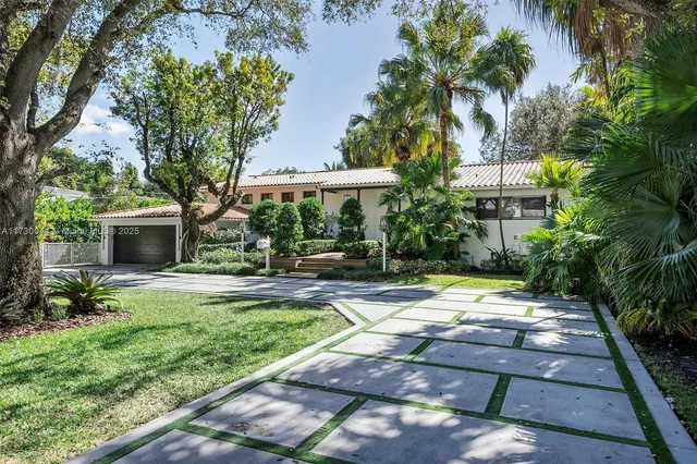 a view of a backyard with couches plants and large trees