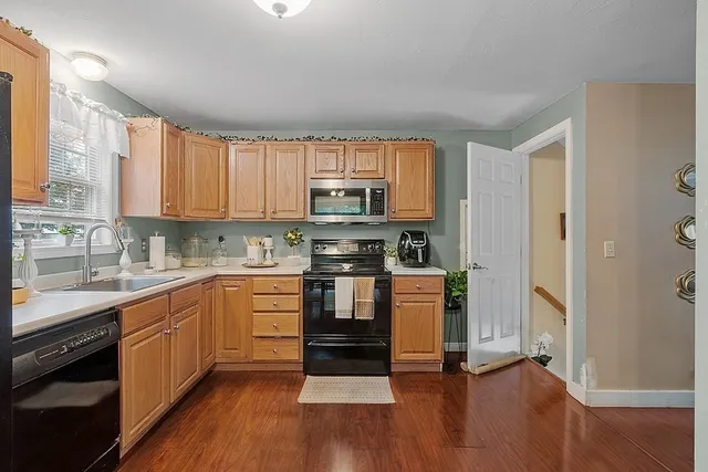 a kitchen with granite countertop a stove top oven a sink dishwasher and a refrigerator with wooden floor