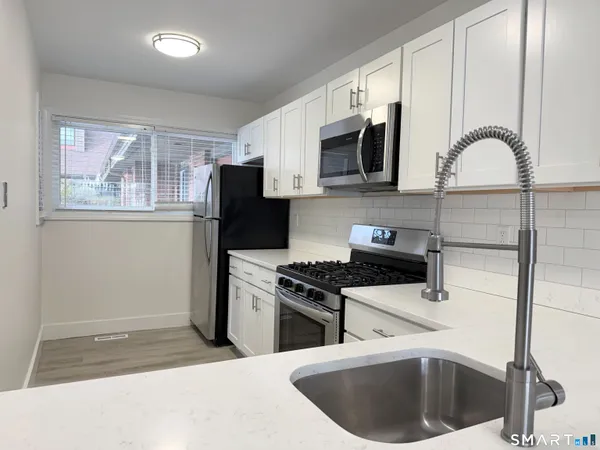 a kitchen with stainless steel appliances granite countertop a stove a sink and a refrigerator