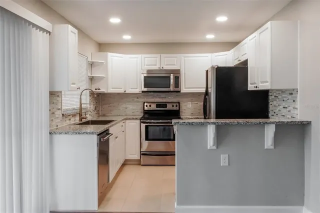 a kitchen with stainless steel appliances granite countertop a stove a sink and a refrigerator