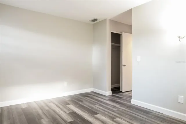 a view of an empty room with wooden floor and closet