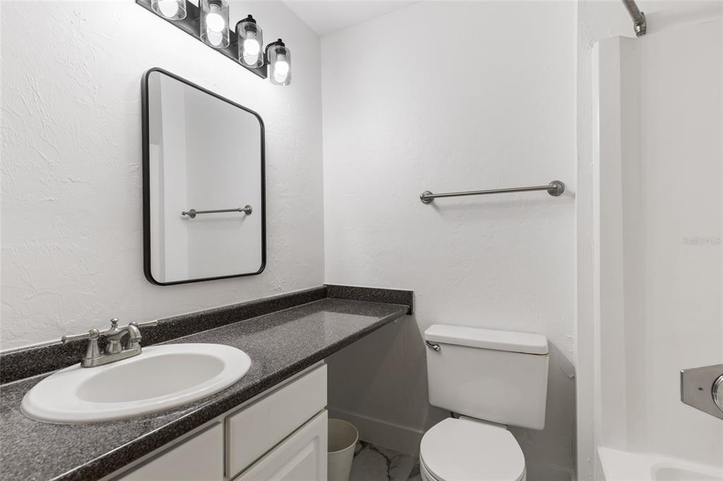 507 Northwest 39th Road, Unit 320 Gainesville, FL 32607 - Photo 22 of 33 a bathroom with a granite countertop toilet sink and mirror