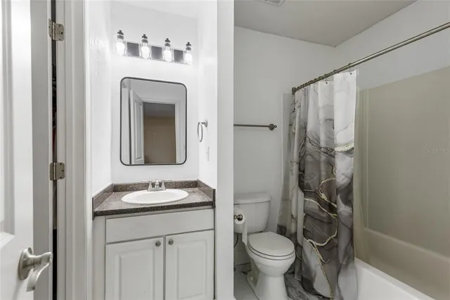 a bathroom with a granite countertop toilet sink and mirror