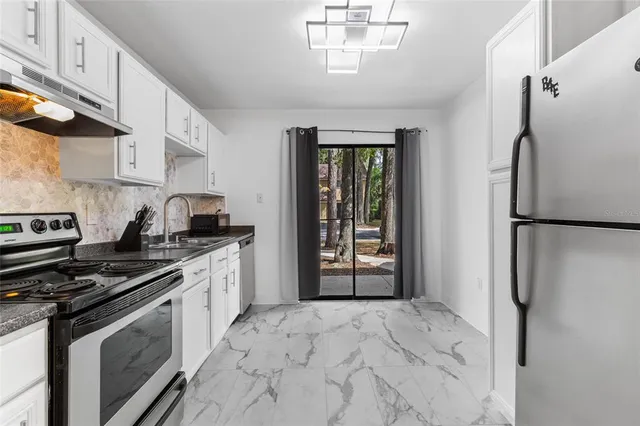 a kitchen with stainless steel appliances granite countertop a refrigerator a stove and a sink