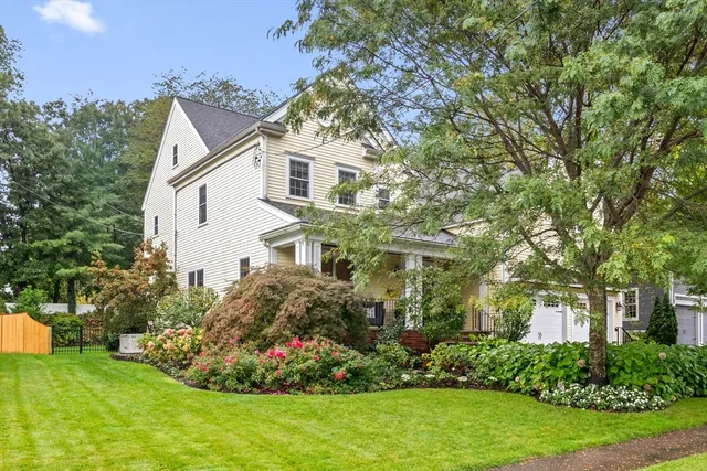a view of a white house with a big yard and potted plants