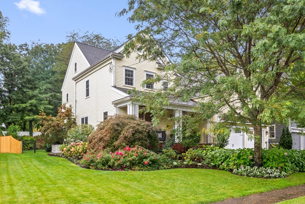 a view of a white house with a big yard and potted plants