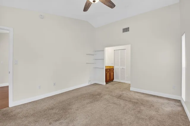 an empty room with ceiling fan and window