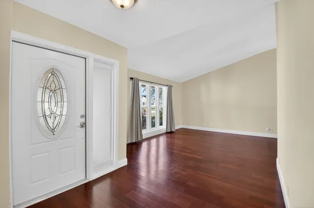 an empty room with wooden floor mirror and windows