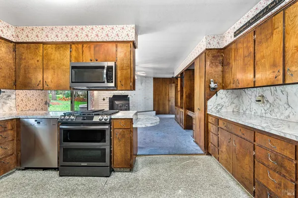 wooden floor in an empty room with a fireplace and a ceiling fan
