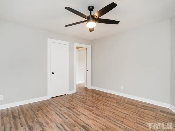 an empty room with wooden floor and ceiling fan