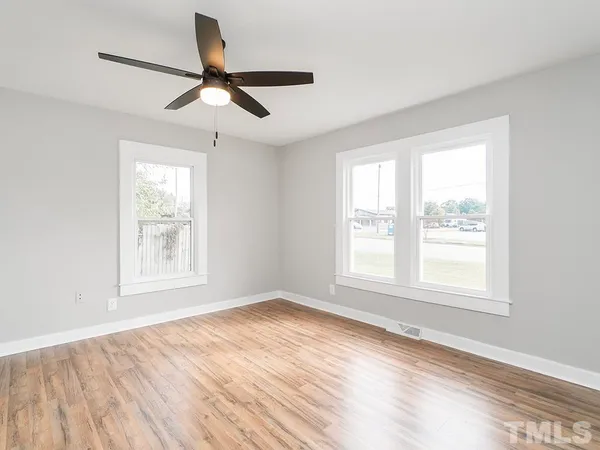 a view of an empty room with wooden floor and a window