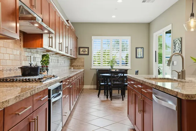 a kitchen with kitchen island granite countertop a sink a counter top space appliances and cabinets