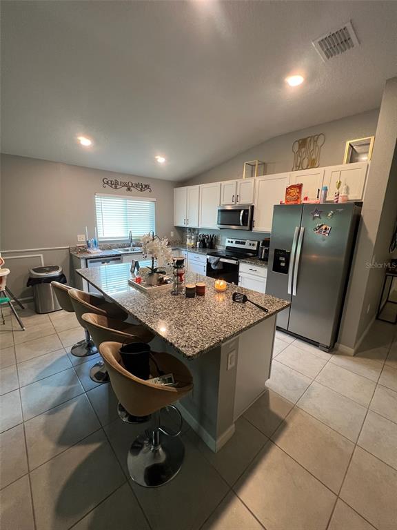 2489 Bulrush Drive St. Cloud, FL 34769 - Photo 7 of 22 a kitchen with granite countertop a table chairs microwave and cabinets