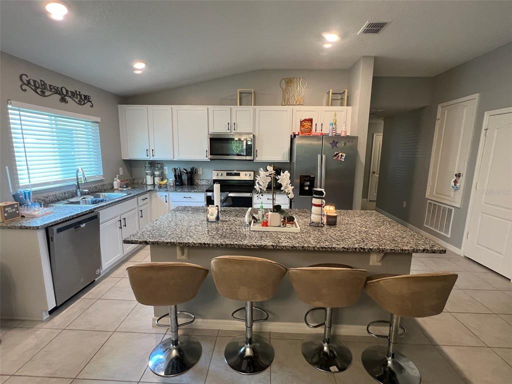 2489 Bulrush Drive St. Cloud, FL 34769 - Photo 8 of 22 a kitchen with granite countertop counter space a sink appliances and cabinets