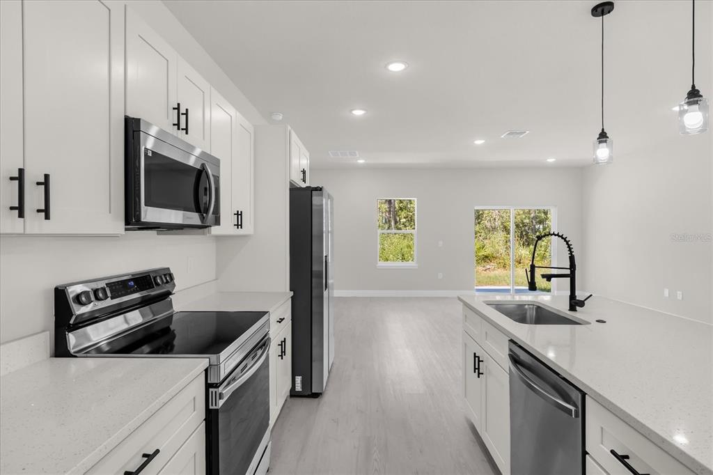 15782 Southwest 52nd Ave Road Ocala, FL 34473 - Photo 11 of 34 a kitchen with stainless steel appliances a sink a stove a microwave a refrigerator a sink and dishwasher with wooden floor