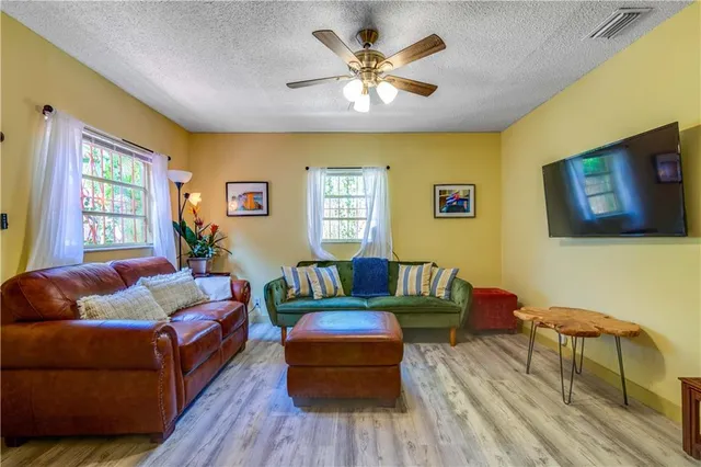 a living room with couches and a flat screen tv with kitchen view