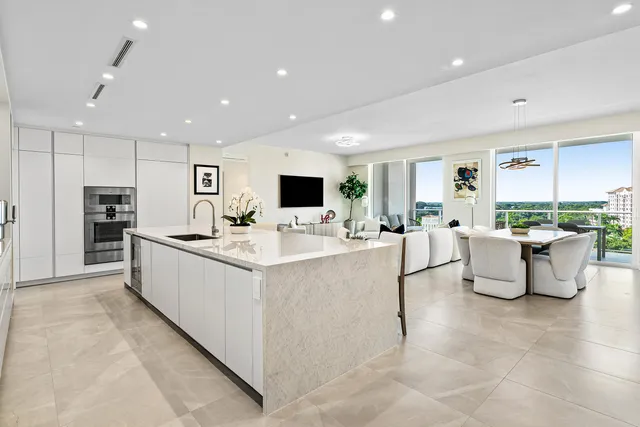 a large white kitchen with kitchen island a island a stove a sink a counter space and a view of kitchen