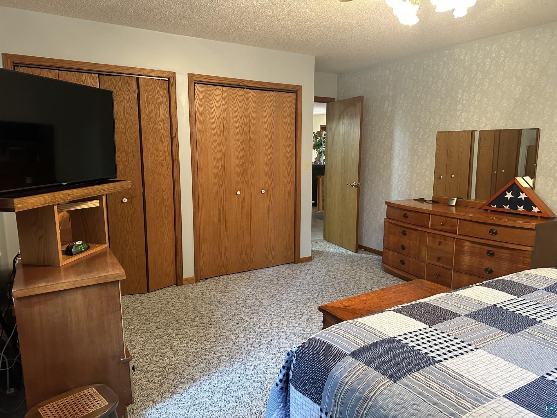 81 Hautaluoma Road Esko, MN 55733 - Photo 20 of 43 Bedroom featuring two sets of wood-finish bi-fold closet doors, textured wall covering, and neutral patterned carpeting