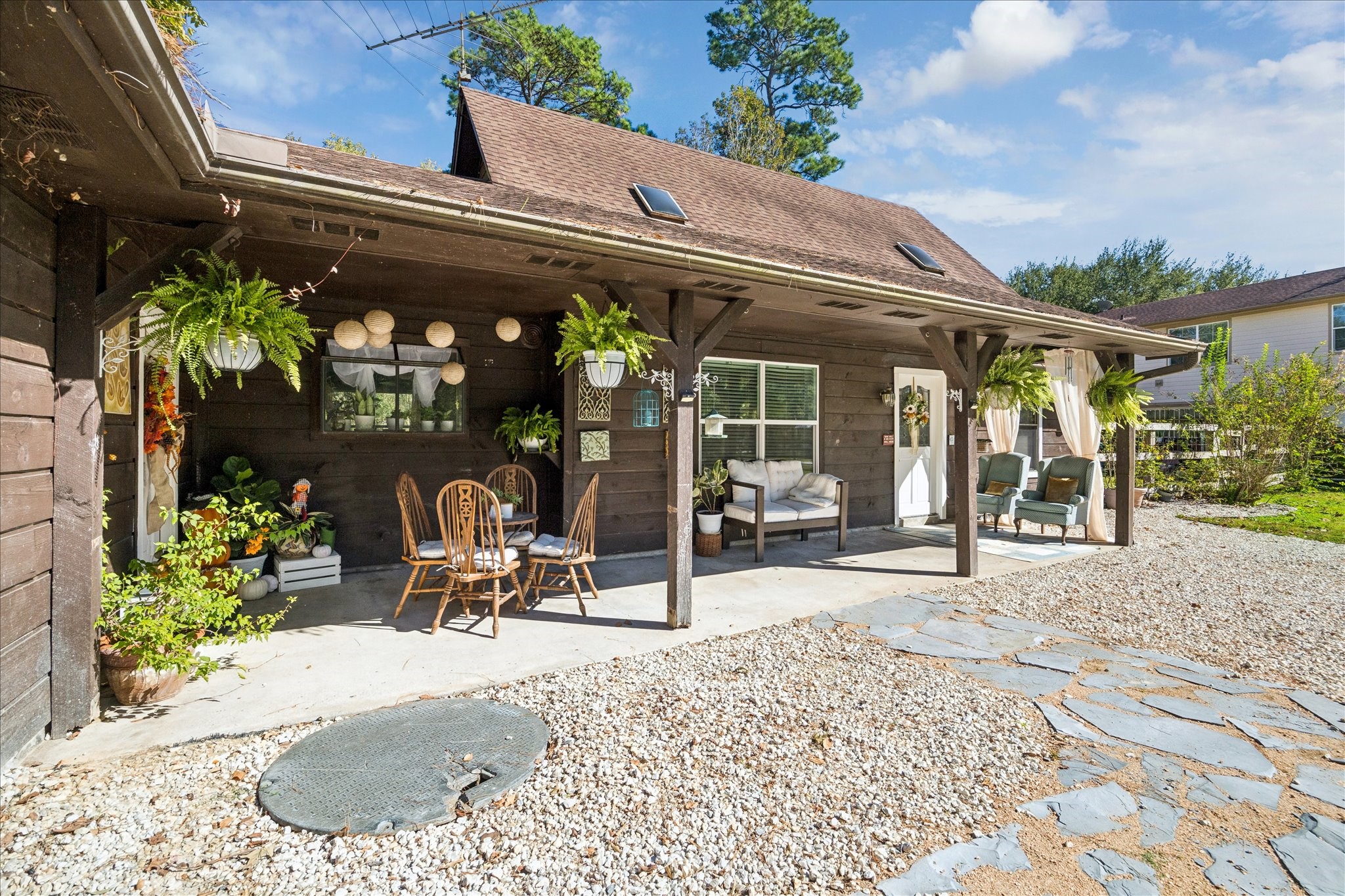 6 B Davidson Lane Huffman, TX 77336 - Photo 4 of 20 Charming outdoor space with a covered patio featuring wooden beams that you could easliy hang plants on. Imagine sitting in a cozy seating area having dinner al fresco, perfect for relaxation and entertaining. The patio overlooks a gravel and stone path, adding to the rustic appeal.