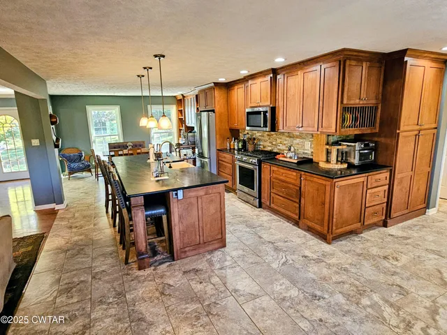 a kitchen with stainless steel appliances granite countertop a stove top oven a sink dishwasher and cabinets with wooden floor