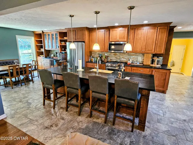 a kitchen with granite countertop wooden cabinets a dining table and chairs