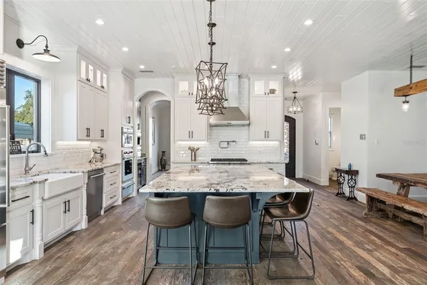 a kitchen with stainless steel appliances kitchen island granite countertop a table chairs and white cabinets