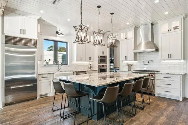 a large kitchen with stainless steel appliances kitchen island granite countertop a large center island and a stove top oven