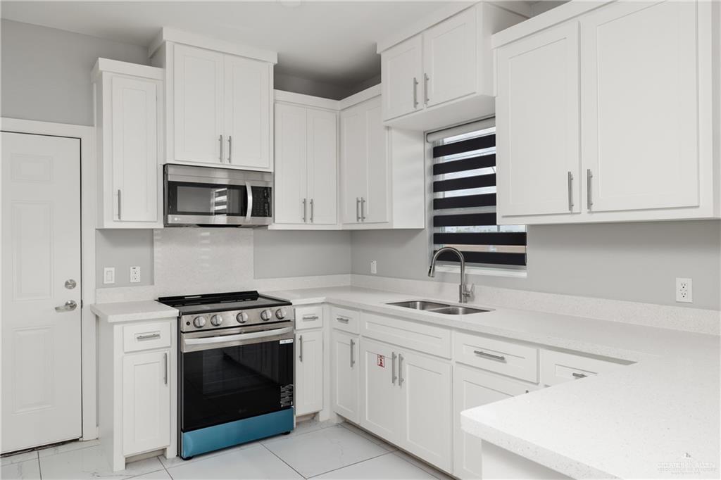 904 Deluxe Street Alamo, TX 78516 - Photo 4 of 11 Kitchen featuring appliances with stainless steel finishes, white cabinetry, light stone counters, and light tile patterned floors