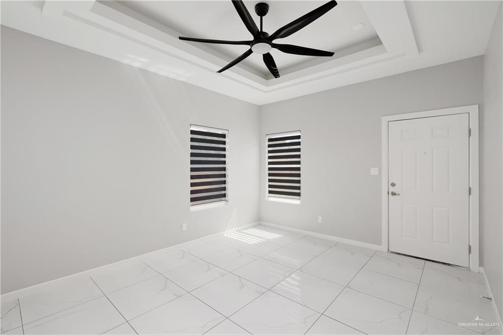 904 Deluxe Street Alamo, TX 78516 - Photo 5 of 11 Spare room featuring light marble finish flooring, a tray ceiling, and ceiling fan
