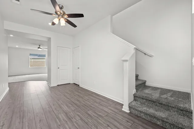 an empty room with wooden floor fan and windows