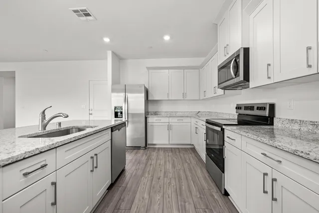a kitchen with a sink dishwasher stove and white cabinets with wooden floor