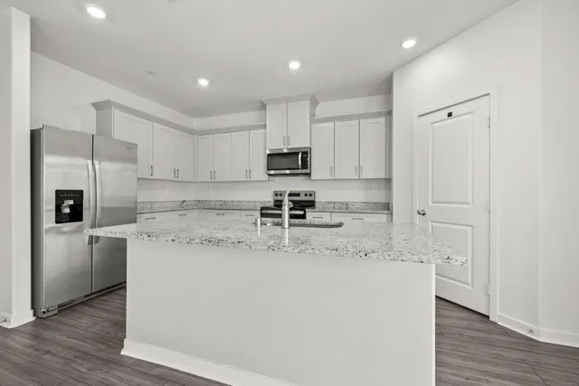 a kitchen with stainless steel appliances granite countertop a sink a stove a refrigerator a microwave and cabinets