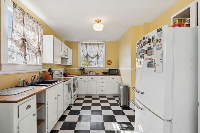 a kitchen with a checkered floor and white cabinets