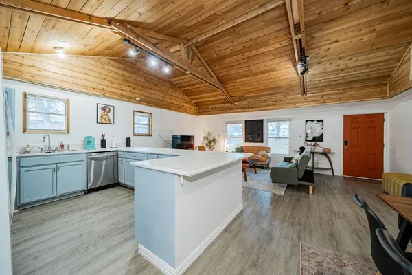 a kitchen with sink a stove and chairs with wooden floor