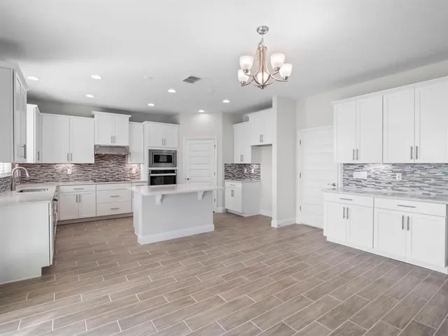 a large white kitchen with stainless steel appliances granite countertop a stove a sink and a refrigerator