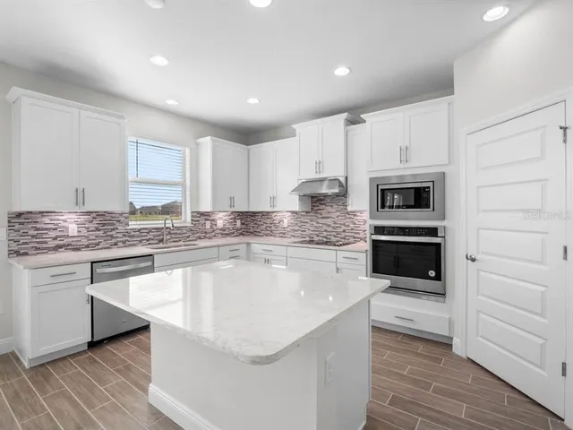 a kitchen with granite countertop white cabinets and appliances