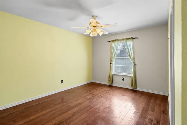an empty room with wooden floor chandelier and windows
