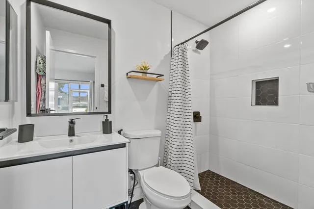 a bathroom with a sink a toilet a mirror and shower