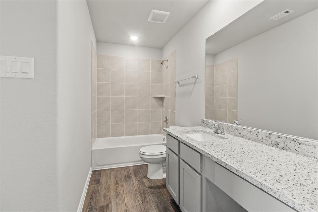 6909 Cattle Car Way Crowley, TX 76036 - Photo 16 of 24 a bathroom with a granite countertop sink a toilet and shower