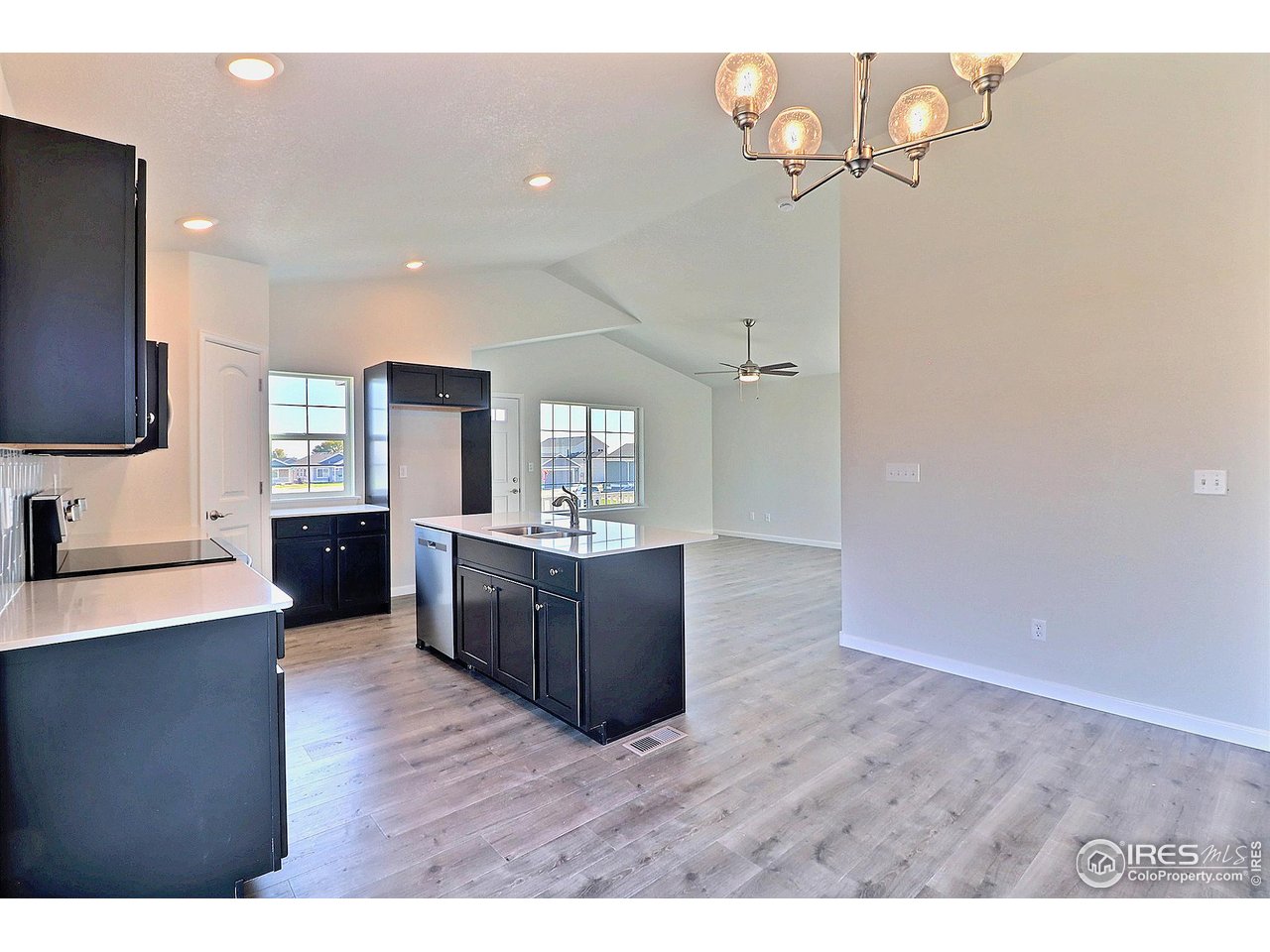 4301 Rockcress Road Evans, CO 80620 - Photo 10 of 26 a kitchen with stainless steel appliances granite countertop a refrigerator a sink dishwasher a stove and a dining table with wooden floor