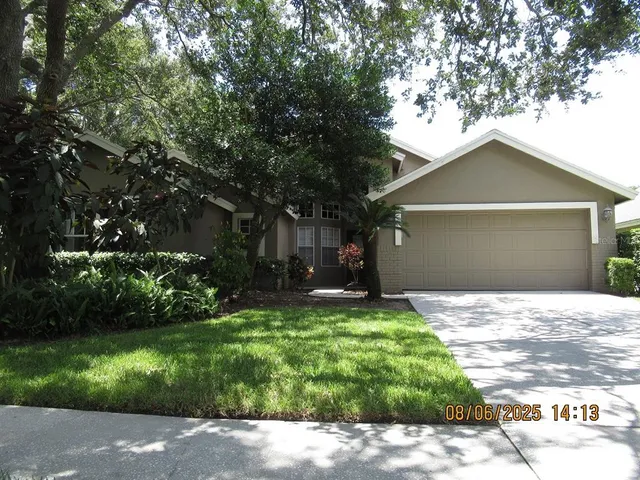 a view of a house with a yard plants and large tree