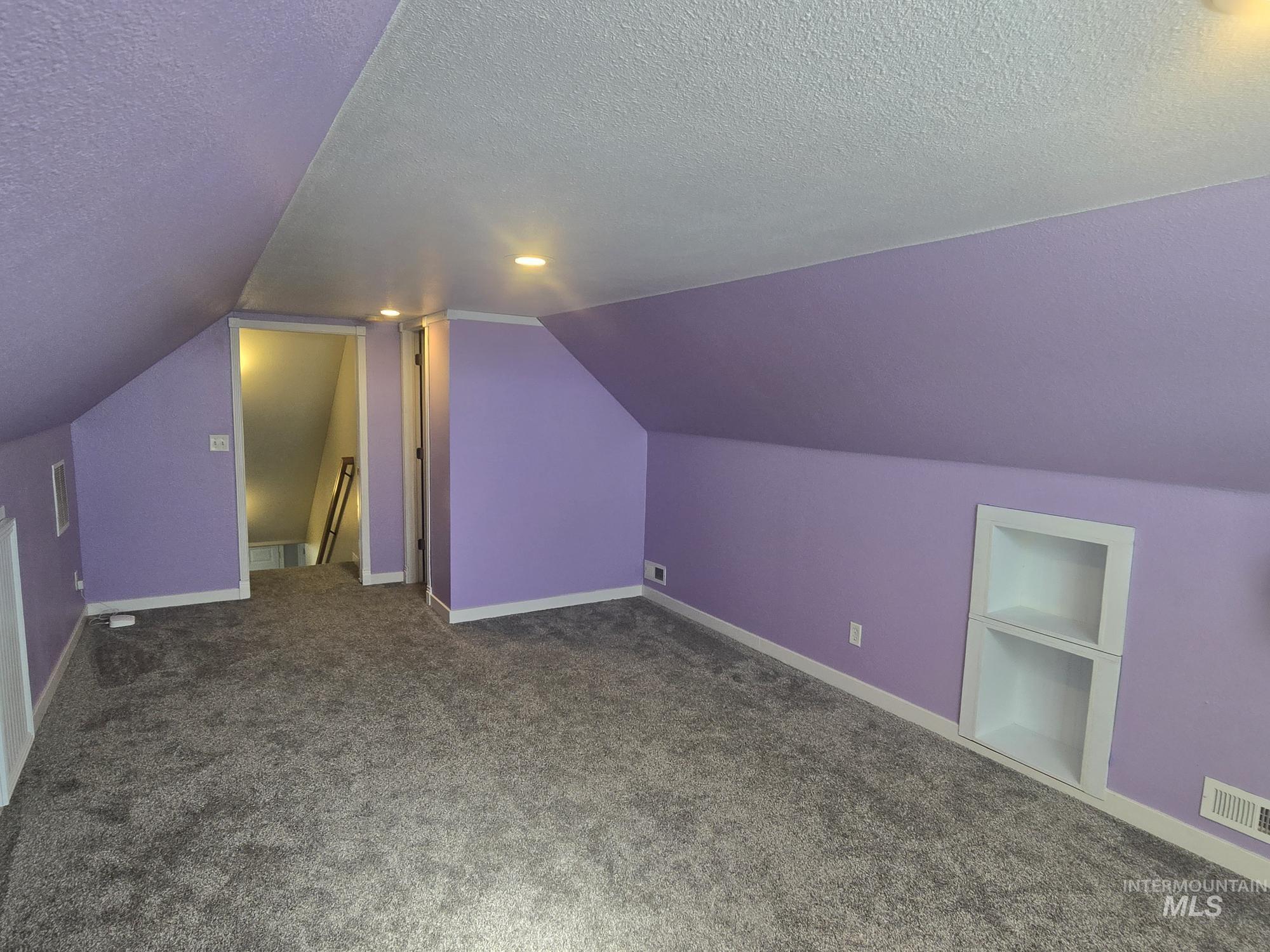2480 West 9th Street Weiser, ID 83672 - Photo 4 of 17 Spacious room featuring sloped ceilings, recessed lighting, built-in shelving, carpet flooring, and white baseboards