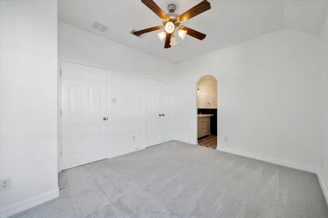 an empty room with closet and a ceiling fan