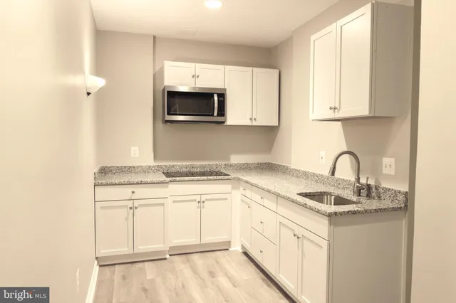 a kitchen with granite countertop white cabinets and white appliances