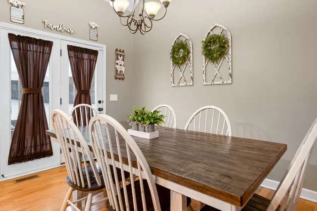 a kitchen with stainless steel appliances granite countertop a stove top oven a sink dishwasher a dining table and chairs with wooden floor