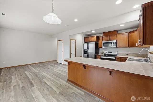 a large kitchen with stainless steel appliances wooden floors and a view of living room